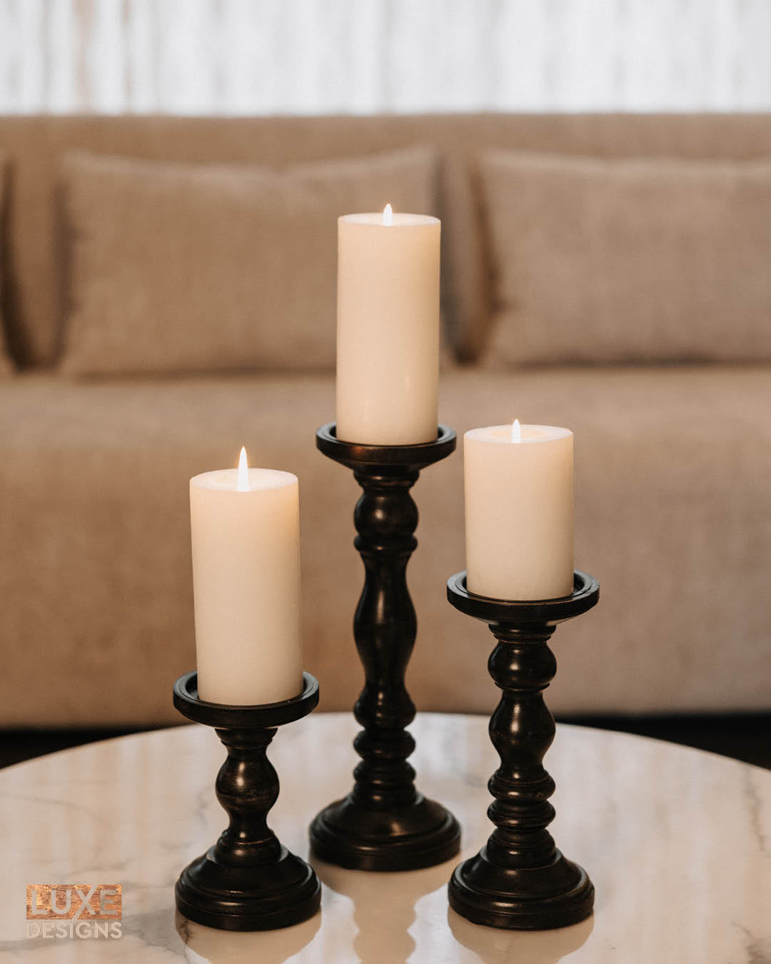 Set of three black wooden pillar candle holders at graduated heights